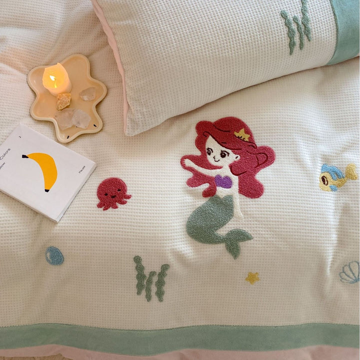 Cozy bedding set with plush border, embroidered appliqués, and reversible function