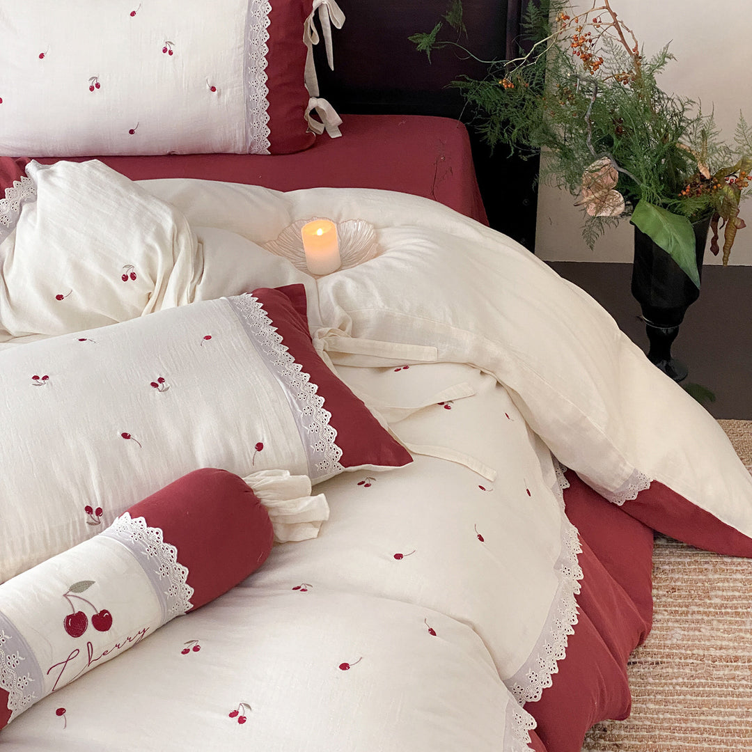 Country-style bedding set with cherry embroidery, lace trim, and decorative neck roll