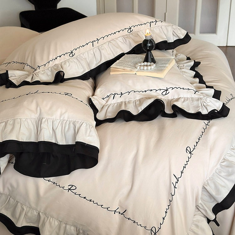 Luxurious cotton satin bedding set with ruffle, contrasting piped trim, and calligraphic embroidery