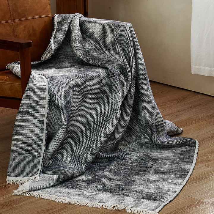 Large cozy living blanket made of cotton blend fabric with geometric jacquard pattern and fringed hem