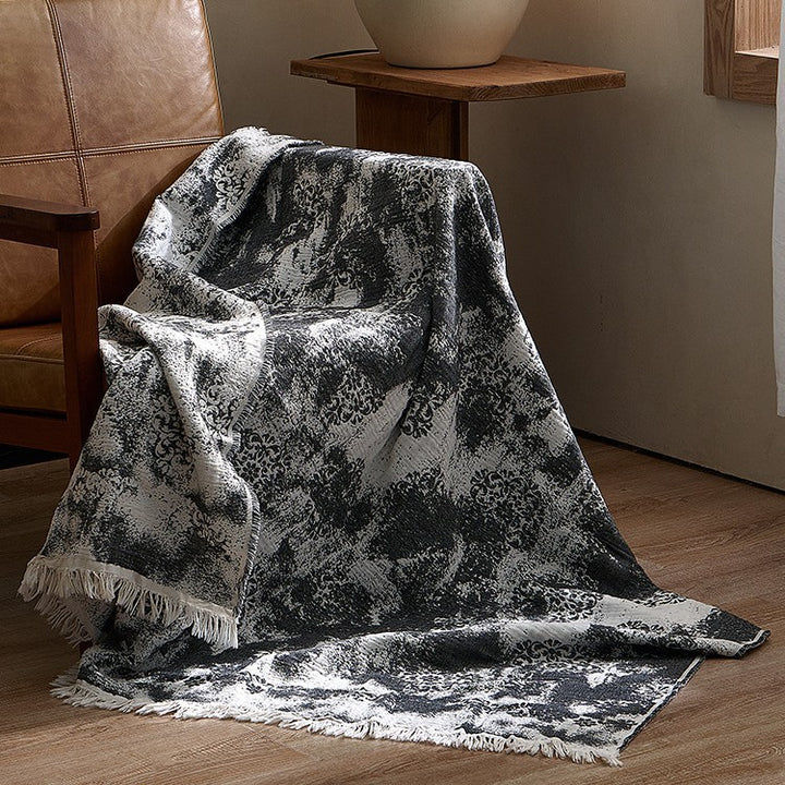 Large cozy living blanket made of cotton blend fabric with geometric jacquard pattern and fringed hem