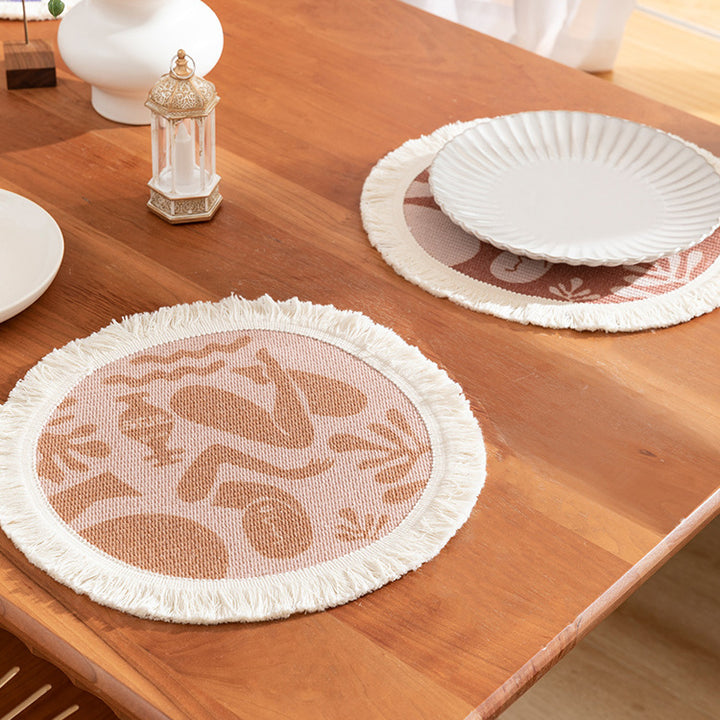 Round woven placemat with fringes and abstract figure motif Kalsten