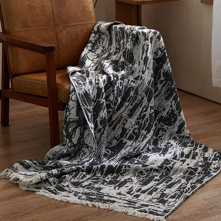 Large cozy living blanket made of cotton blend fabric with geometric jacquard pattern and fringed hem