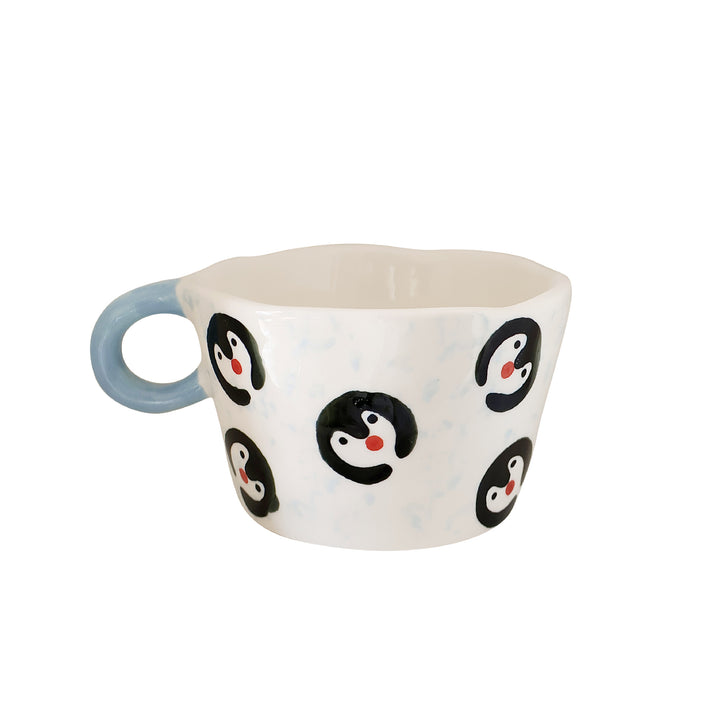 Ceramic coffee mug with hand-painted penguin designs and ergonomic handle