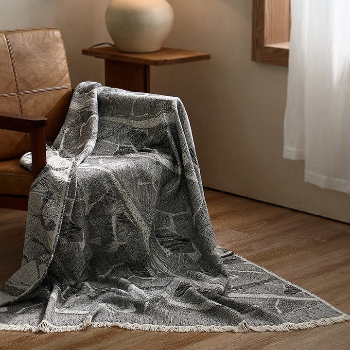 Large cozy living blanket made of cotton blend fabric with geometric jacquard pattern and fringed hem
