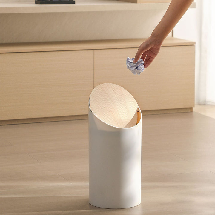 Modern oval waste bin with rotating wooden lid and noise-dampening opening