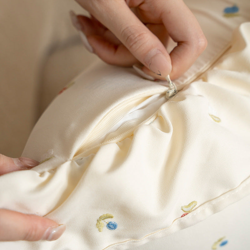 Decorative cushion with ruffles and embroidered flower pattern