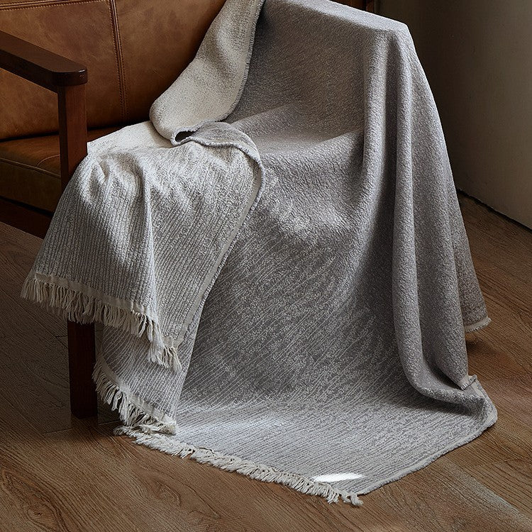 Large cozy living blanket made of cotton blend fabric with geometric jacquard pattern and fringed hem