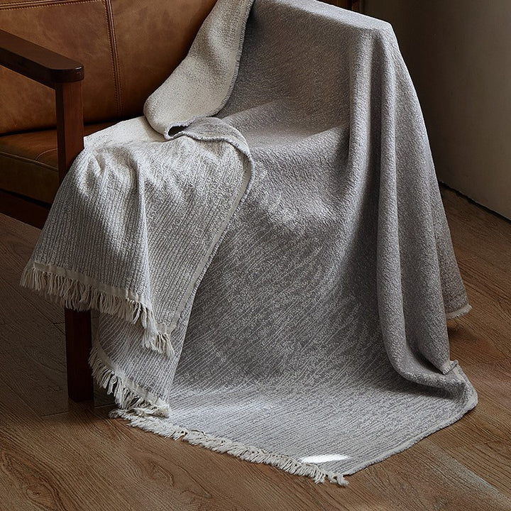 Large cozy living blanket made of cotton blend fabric with geometric jacquard pattern and fringed hem
