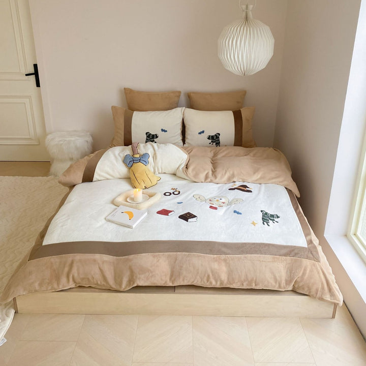 Cozy bedding set with plush border, embroidered appliqués, and reversible function