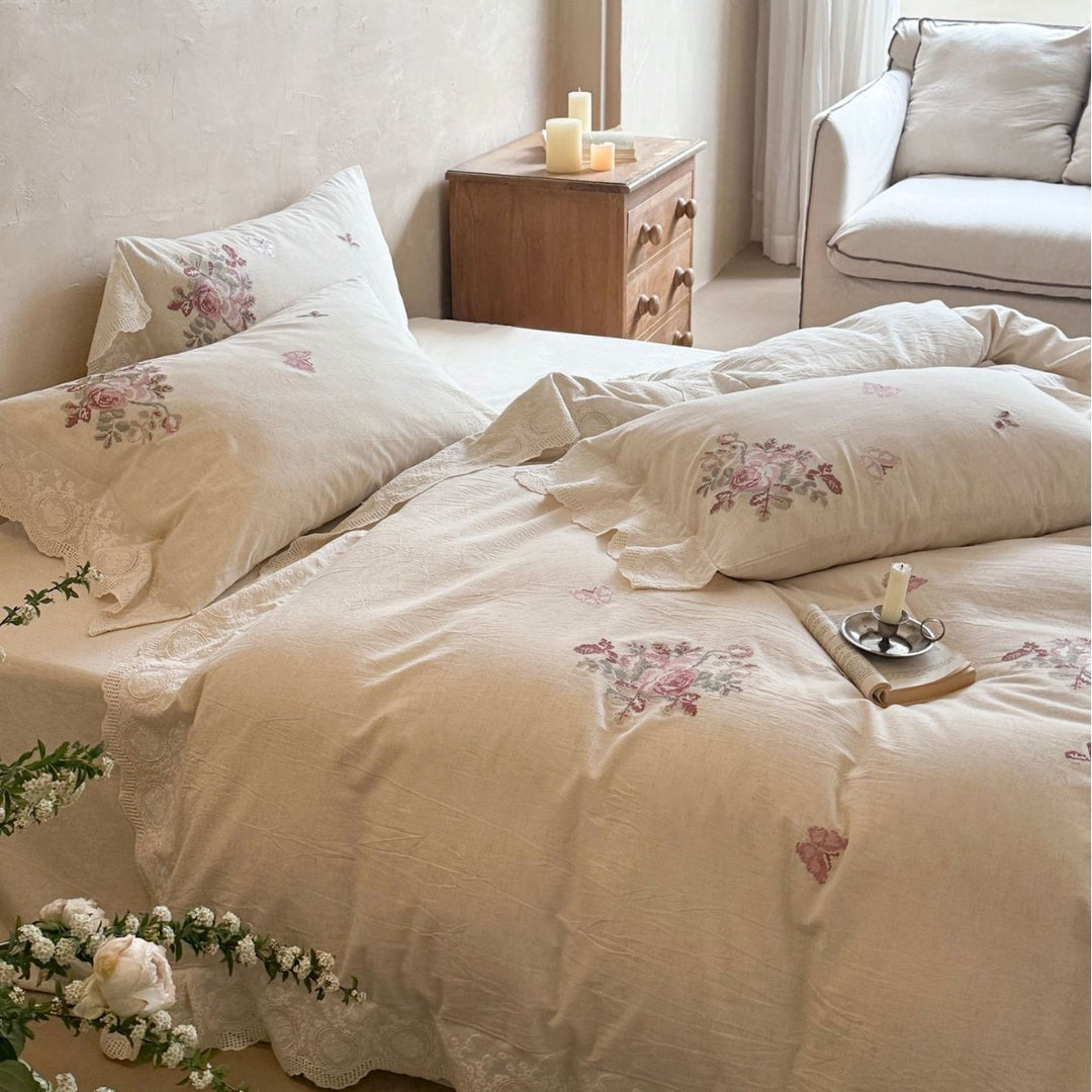 Embroidered cotton-linen bedding set with rose motifs, lace ruffle, and natural texture