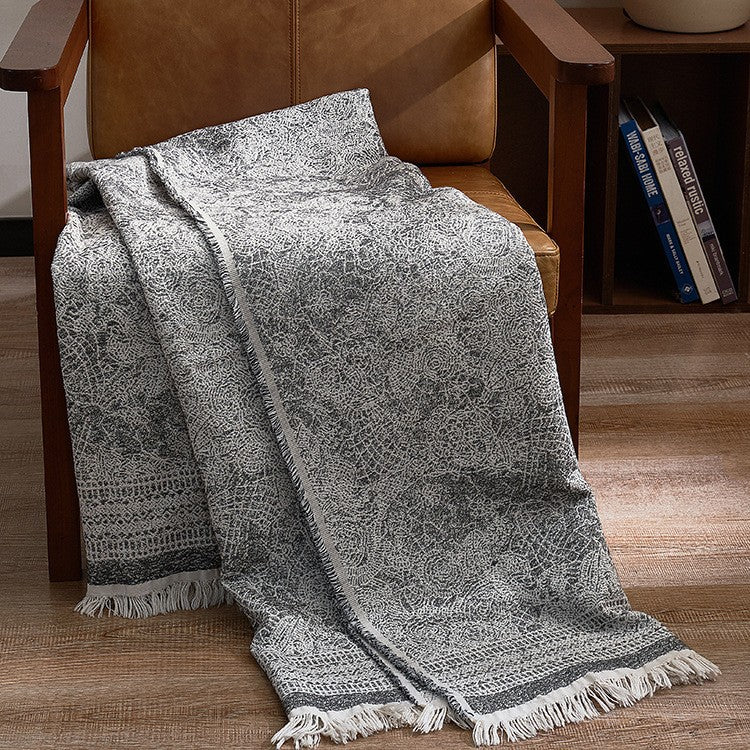 Large cozy living blanket made of cotton blend fabric with geometric jacquard pattern and fringed hem