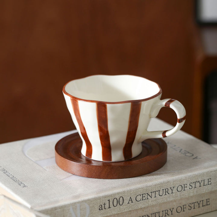 Sculptural ceramic coffee cup with curved rim and distinctive stripe decor