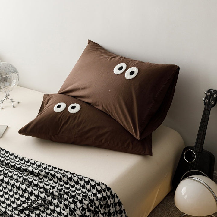 Playful cushion cover set with embroidered eye appliqués made of soft cotton fabric