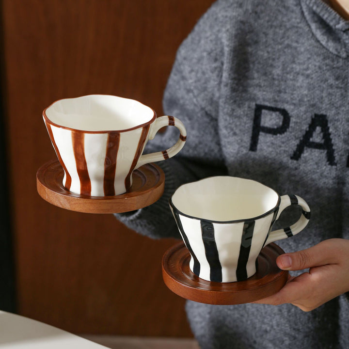 Sculptural ceramic coffee cup with curved rim and distinctive stripe decor