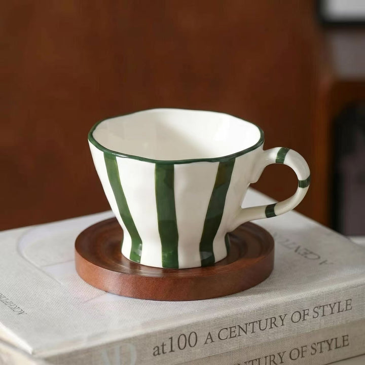 Sculptural ceramic coffee cup with curved rim and distinctive stripe decor