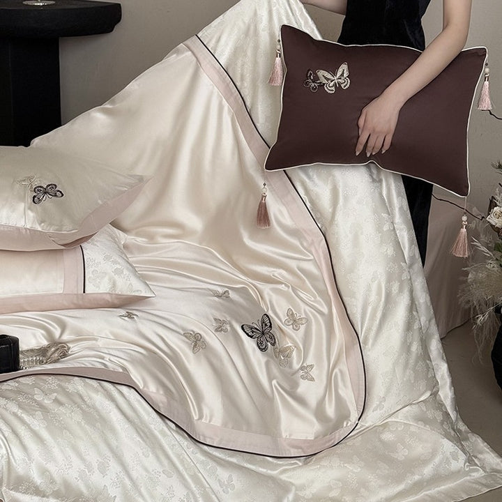 Luxurious satin bedding set with embroidered butterflies, decorative pillows, and tassels