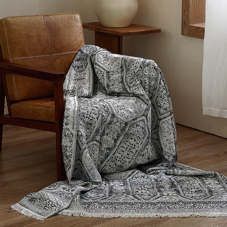 Large cozy living blanket made of cotton blend fabric with geometric jacquard pattern and fringed hem