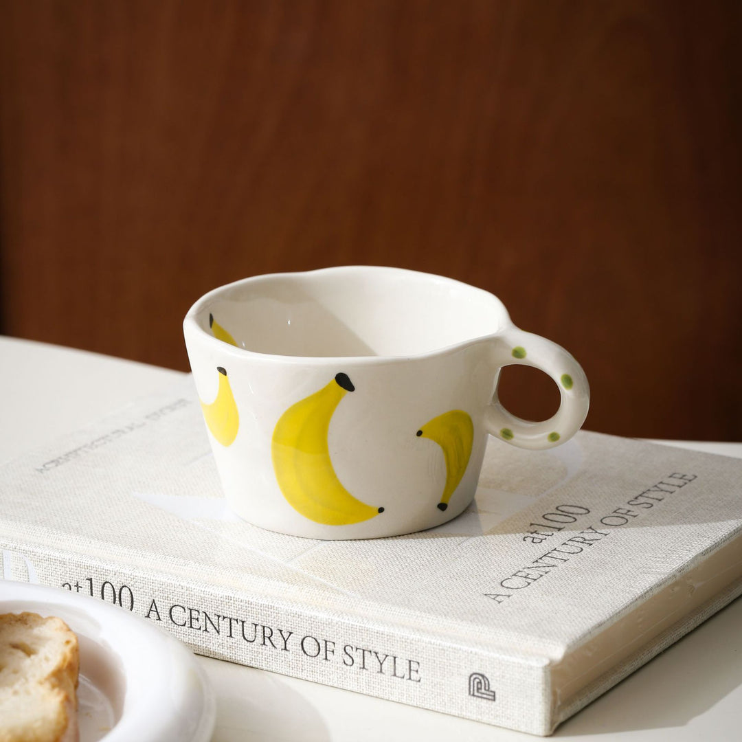 Ceramic mug with hand-painted banana illustration and round handle