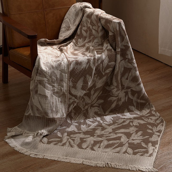 Large cozy living blanket made of cotton blend fabric with geometric jacquard pattern and fringed hem