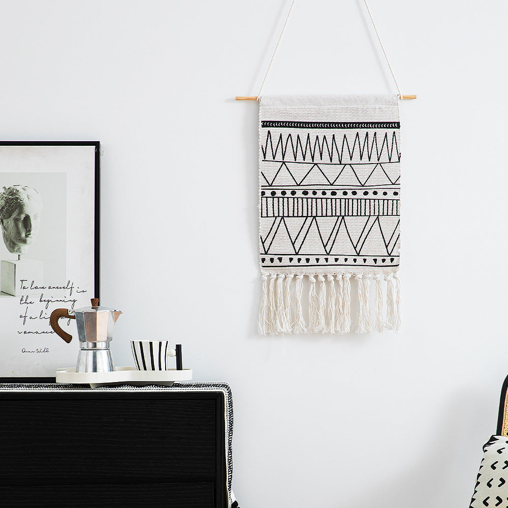 Woven wall hanging made of cotton blend with wooden rod, fringes and geometric ethnic pattern