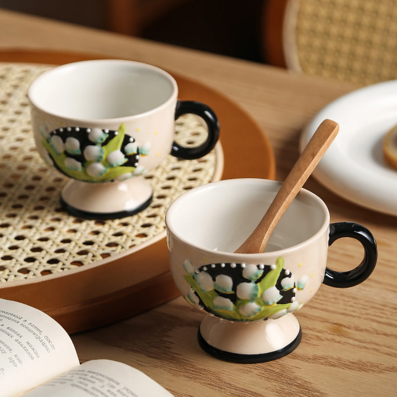 Ceramic foot cup with hand-painted lily of the valley relief and round handle