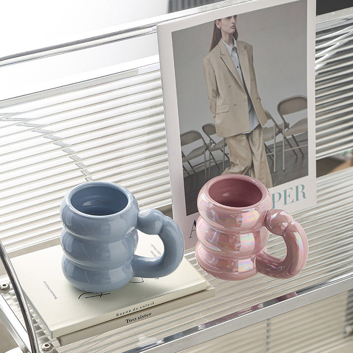 Sculptural ceramic mug with iridescent glaze and curved ring handle