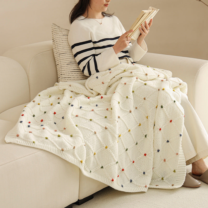Chunky knitted cozy blanket with diamond pattern and colorful knots