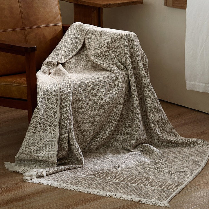 Large cozy living blanket made of cotton blend fabric with geometric jacquard pattern and fringed hem