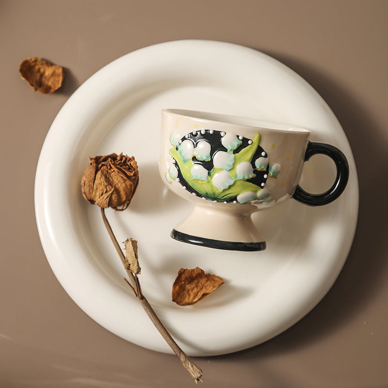 Ceramic foot cup with hand-painted lily of the valley relief and round handle