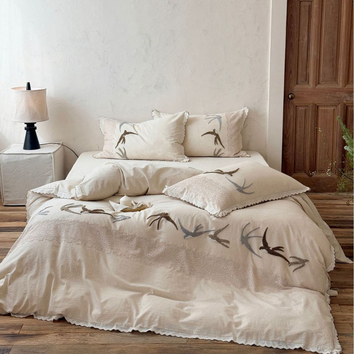 Home decor bedding set made of organic linen with hand-embroidered swallow motif and wavy hem