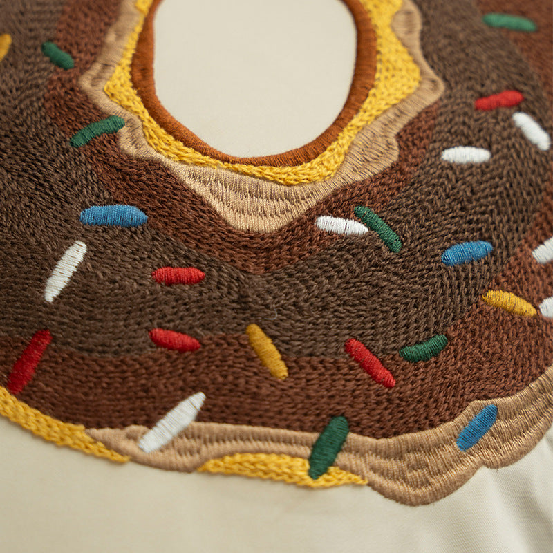 Square decorative cushion with embroidered donut motif and decorative piping edge