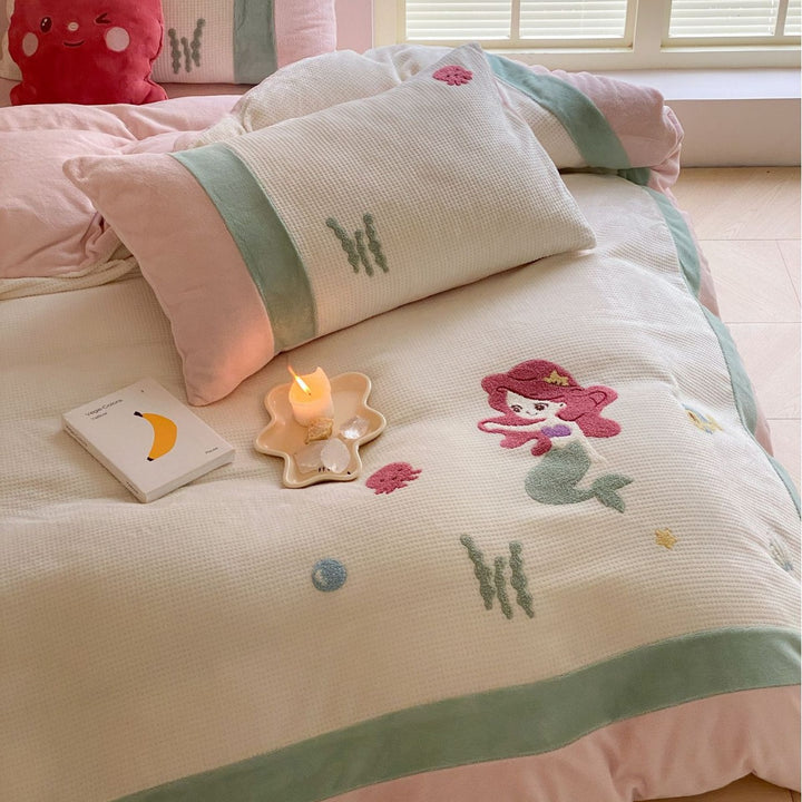 Cozy bedding set with plush border, embroidered appliqués, and reversible function
