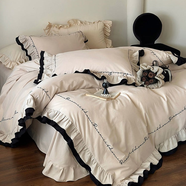 Luxurious cotton satin bedding set with ruffle, contrasting piped trim, and calligraphic embroidery