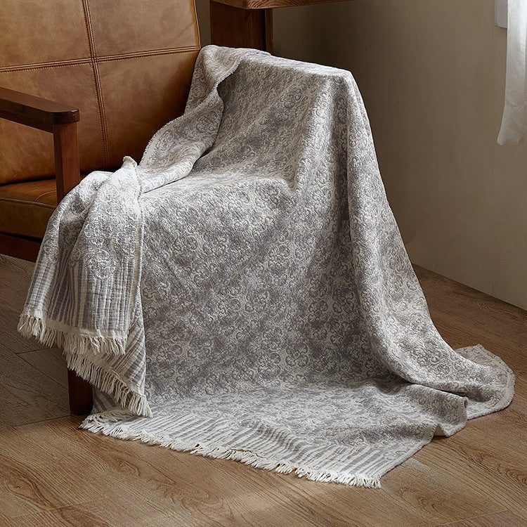 Large cozy living blanket made of cotton blend fabric with geometric jacquard pattern and fringed hem