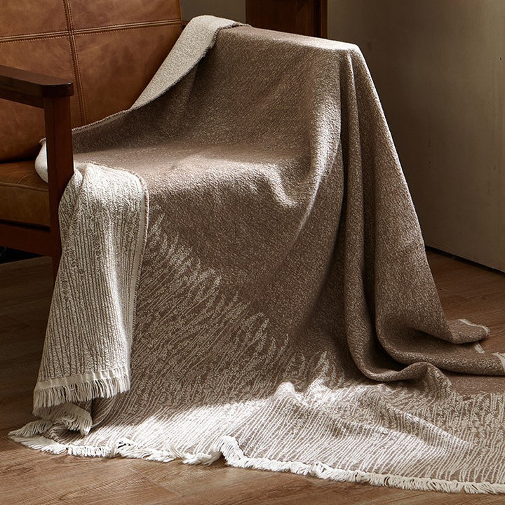 Large cozy living blanket made of cotton blend fabric with geometric jacquard pattern and fringed hem