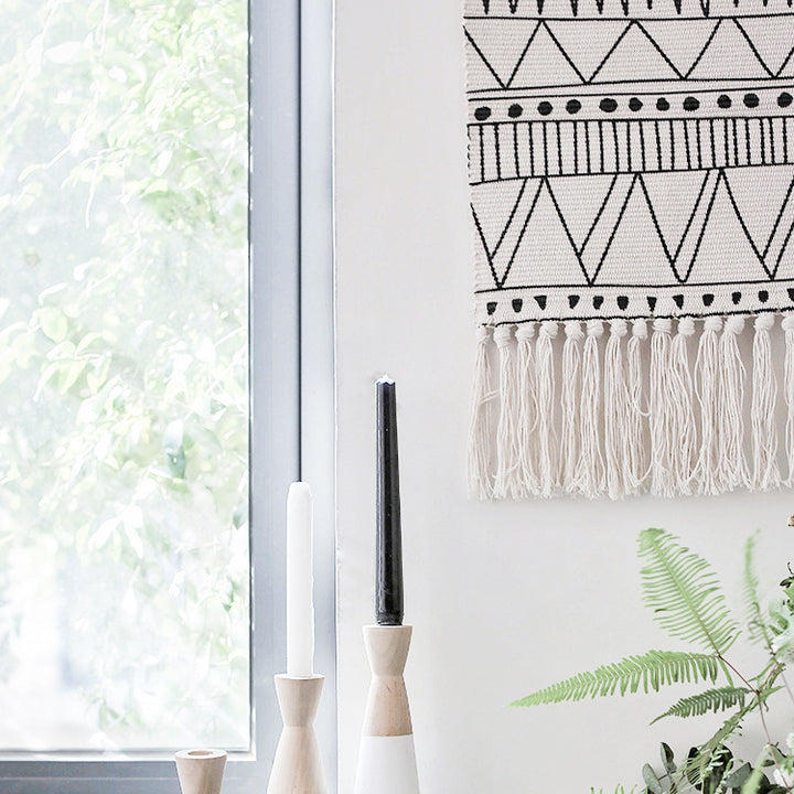 Woven wall hanging made of cotton blend with wooden rod, fringes and geometric ethnic pattern