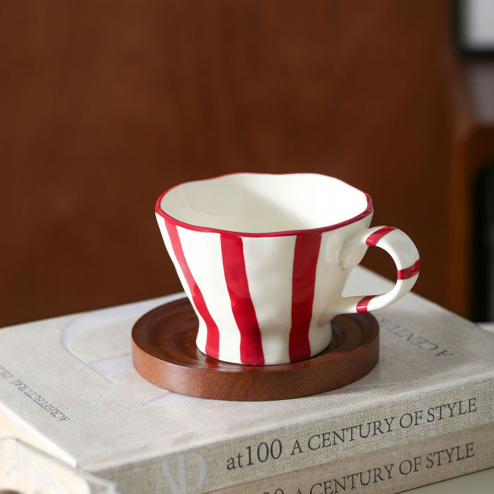 Sculptural ceramic coffee cup with curved rim and distinctive stripe decor
