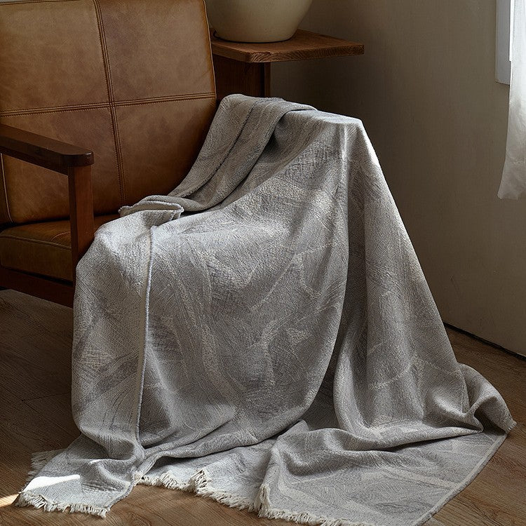 Large cozy living blanket made of cotton blend fabric with geometric jacquard pattern and fringed hem