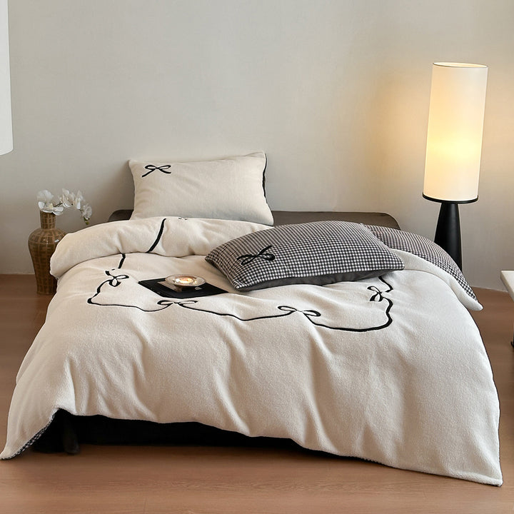 Reversible microfiber bedding set with plush surface, pom-pom corners, and paw embroidery