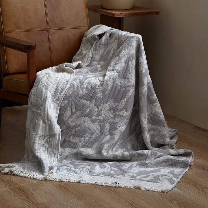 Large cozy living blanket made of cotton blend fabric with geometric jacquard pattern and fringed hem