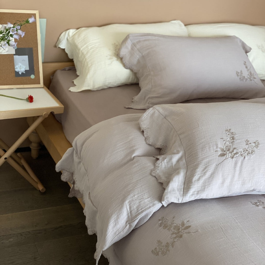 Linen look bedding set with floral embroidery and wavy hem