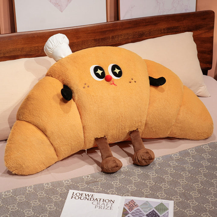 Large cuddly plush pillow in croissant shape with cute cartoon face