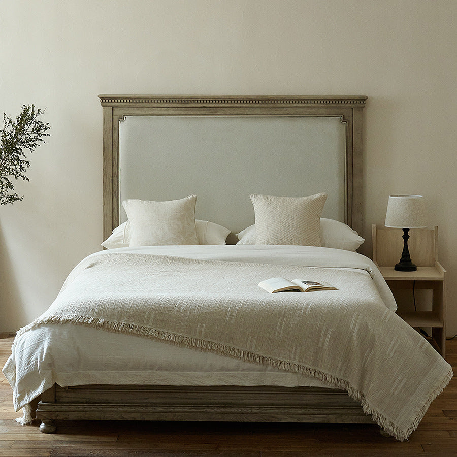 Massive wooden bed with upright slatted headboard and natural linen bedding