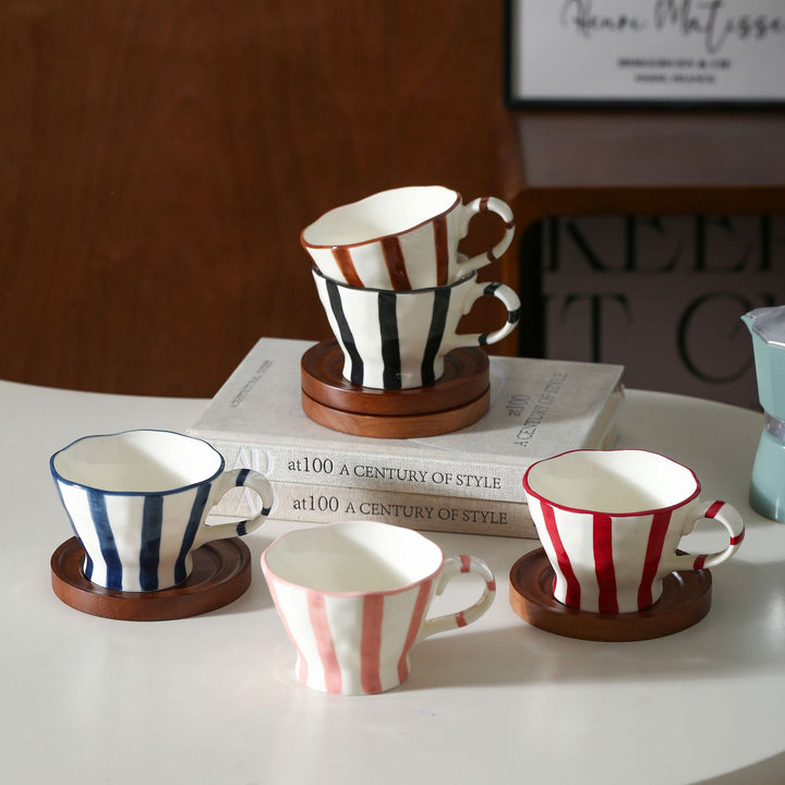 Sculptural ceramic coffee cup with curved rim and distinctive stripe decor