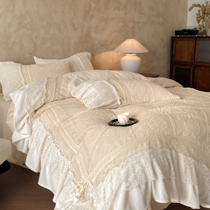 Luxury bedding set with quilted coverlet, lace ruffle, and decorative bed skirt