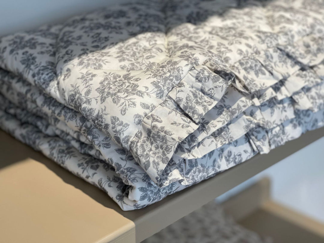 Lightly quilted throw blanket in vintage floral print with ruffled edge