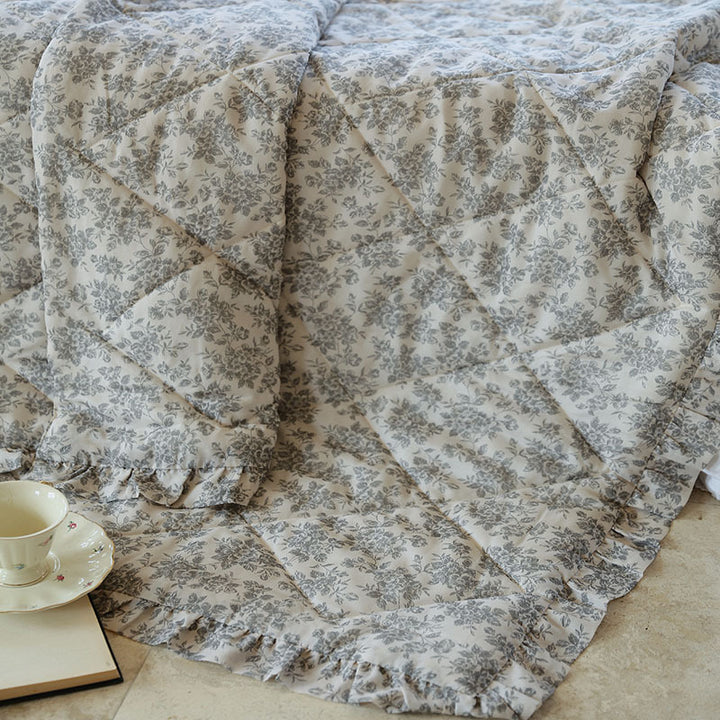 Lightly quilted throw blanket in vintage floral print with ruffled edge