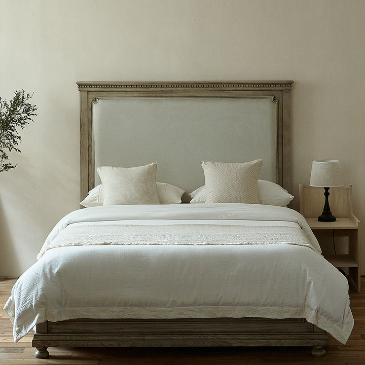 Massive wooden bed with upright slatted headboard and natural linen bedding