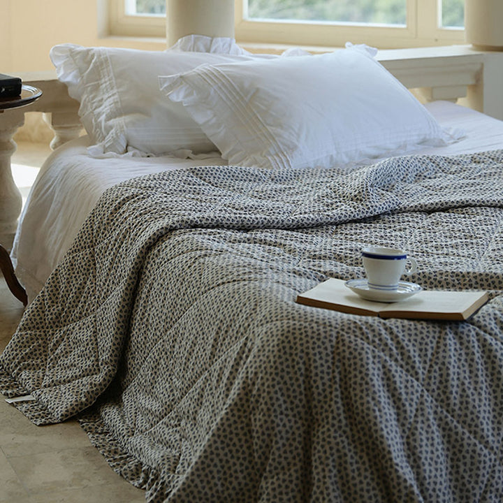 Lightly quilted throw blanket in vintage floral print with ruffled edge